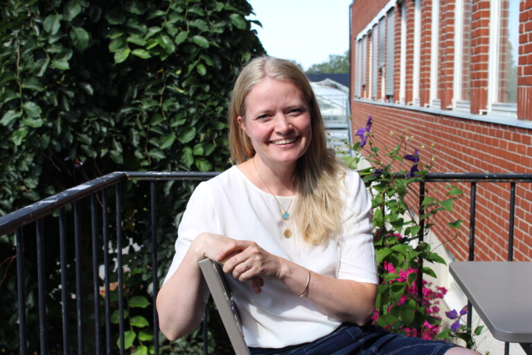 Smilende, lyshåret dame i hvit t-skjorte