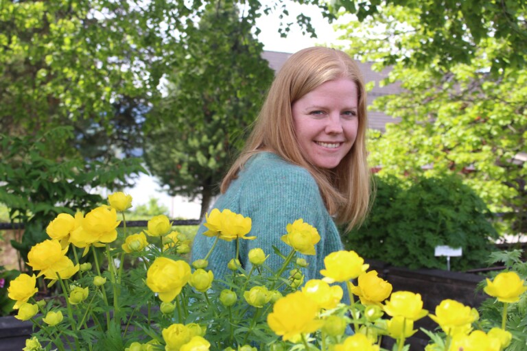 Dame med grønn genser ved giule blomster