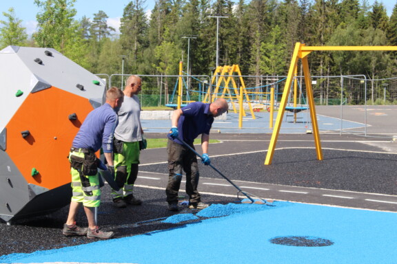 Tre anleggsgartnere som jobber med et lekeplassanlegg