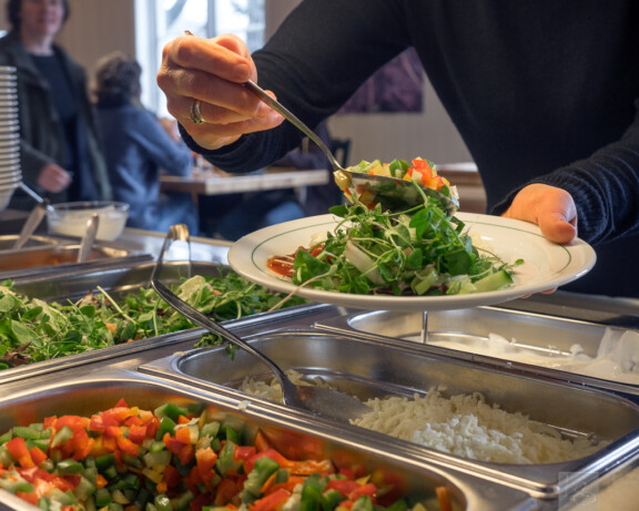 Hender som forsyner seg med mat i kantine