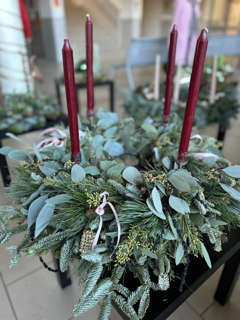 Adventskrans laget av vintergrønt med fire burgunderfargede lys