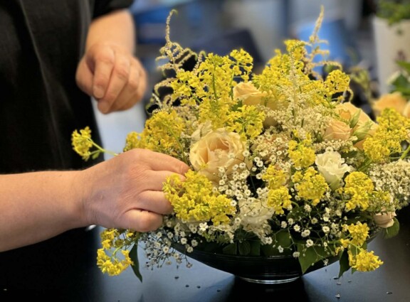 Jente i svart t-skjorte lager dekorasjon med ferskenfargede roser og gule blomster