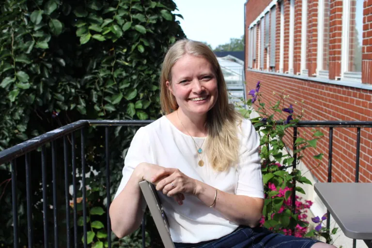 Smilende, lyshåret dame i hvit t-skjorte