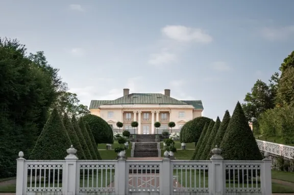 Foto av Gunnebo slott med formklipte spisse trær på rekke