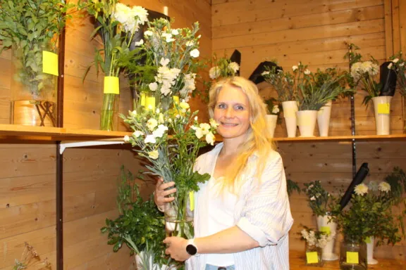 Dame med lyst hår som holder en blomstervase med blomster i