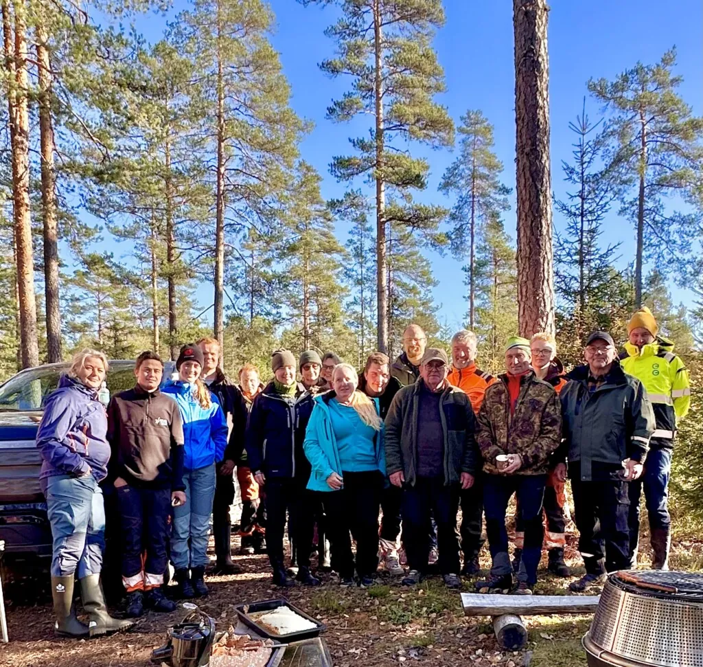 Mange personer avbildet som gruppe ute i skogen