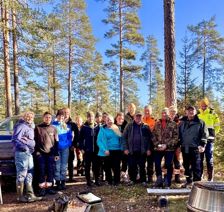 Mange personer avbildet som gruppe ute i skogen