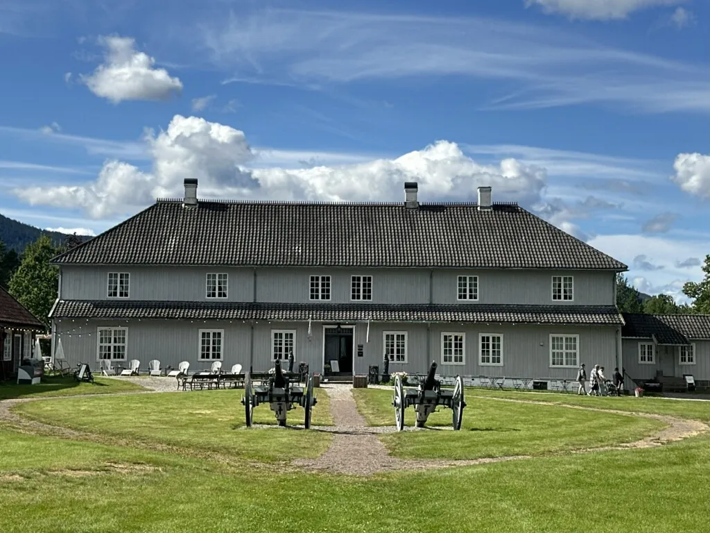 Gammel bygning med valmet tak og to kanoner utenfor