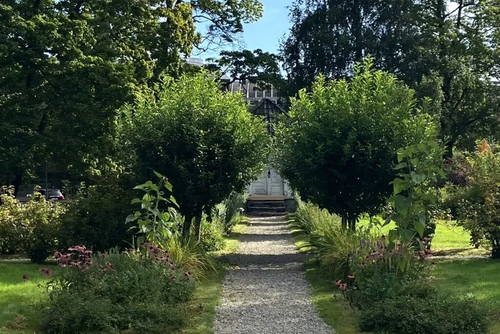 Singelgang, kantet med staudebed og små trær