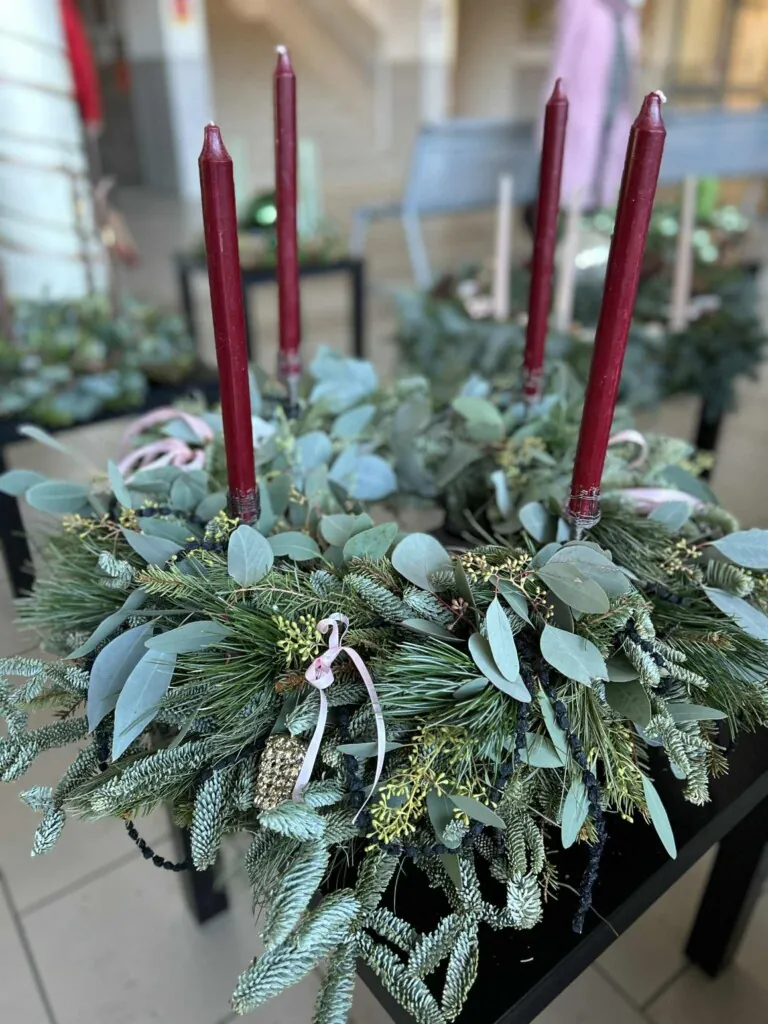 Adventskrans laget av vintergrønt med fire burgunderfargede lys