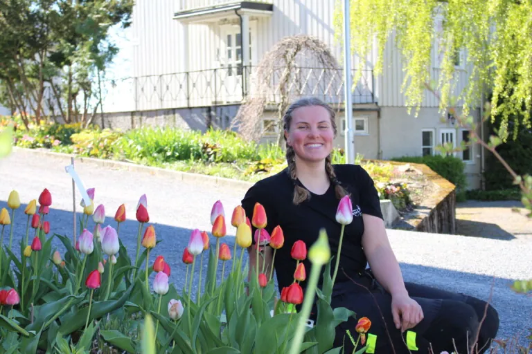 Ung jente som sitter i et bed med tulipaner