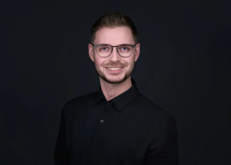 Smilende mann i sort skjorte, briller, bart og skjegg