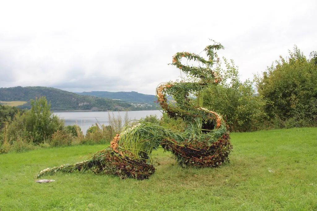 Botanisk arbeid laget av pilgreiner og bær, plassert med Mjøsa i bakgrunnen.