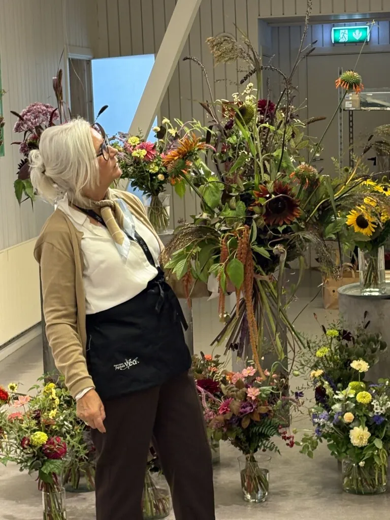Blomsterdekoratør som holder en stor bukett i hånda