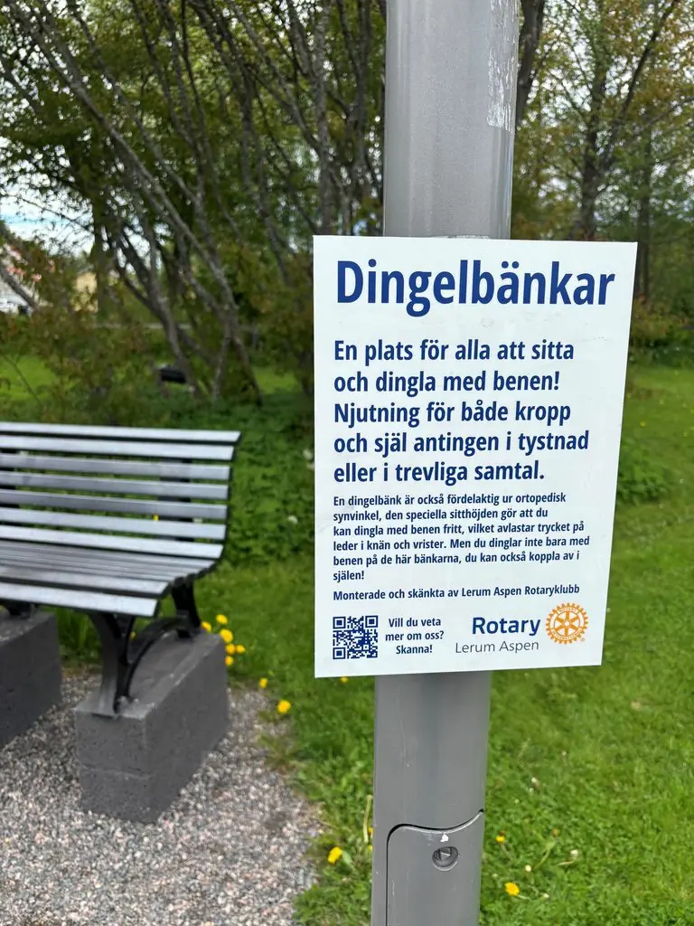 Skilt på stolpe foran en dinglebenk